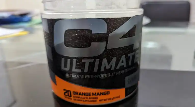 a container of Cellucor C4 Ultimate pre-workout powder in orange mango flavor sitting on a table.