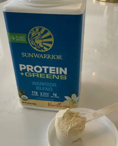 a scoop of the Sunwarrior protein powder next to a jar of the same powder.